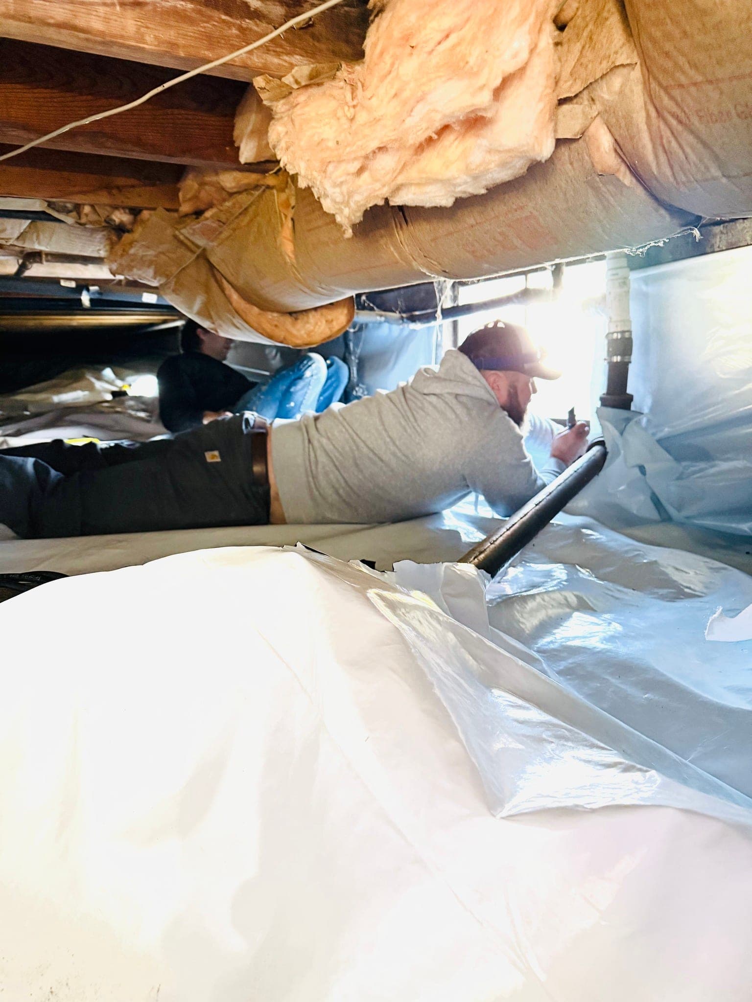 Eagle Air technicians sealing a vapor barrier in a crawl space